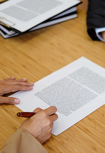Avvocato Andrea Bottoli: Primo piano di un documento appoggiato su un tavolo e la mano di una persona che lo sta firmando